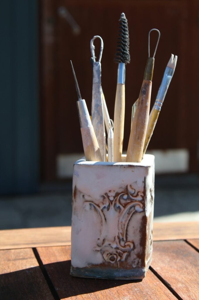 Hand-painted ceramic mug with paintbrushes ready for a bisqueware session