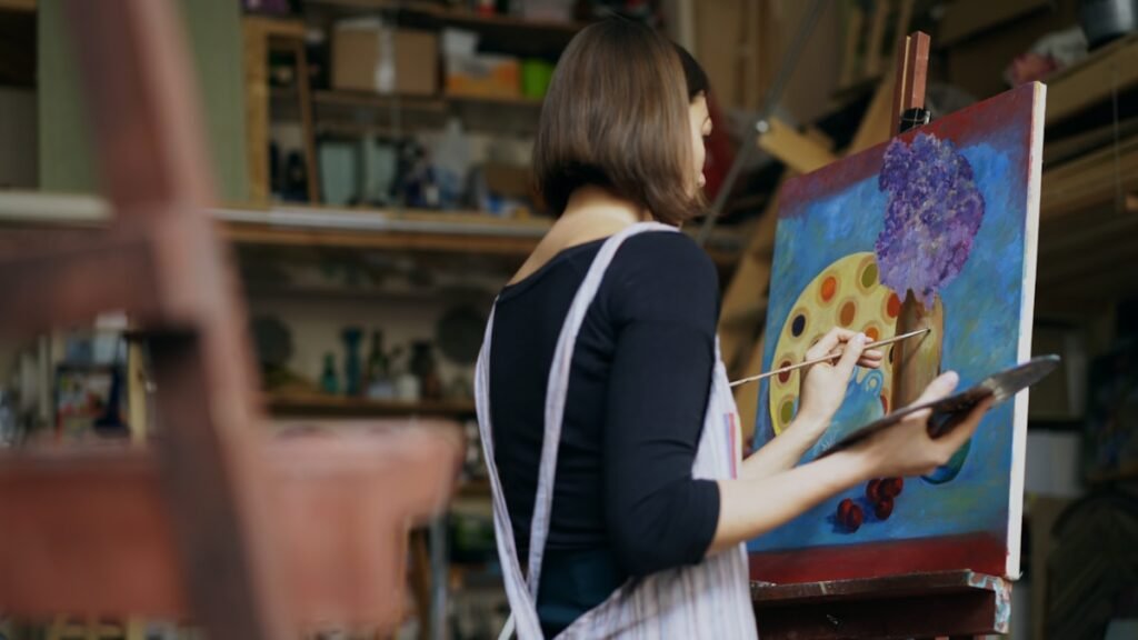 Guest carefully painting an original canvas during a Mug & Muse studio session