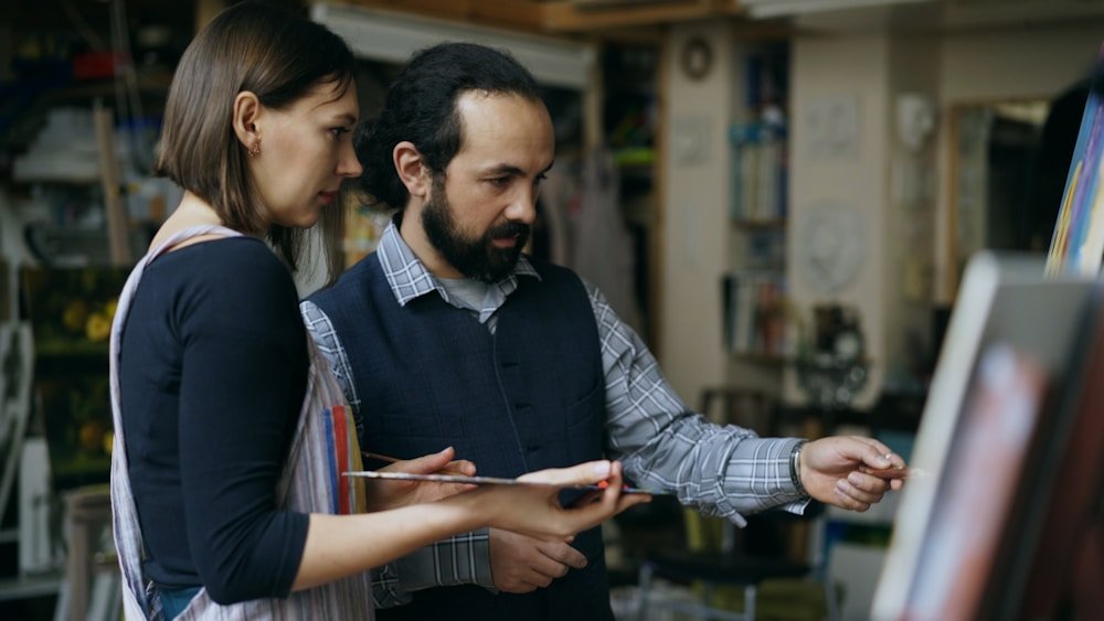 Instructor guiding a guest through a canvas painting technique