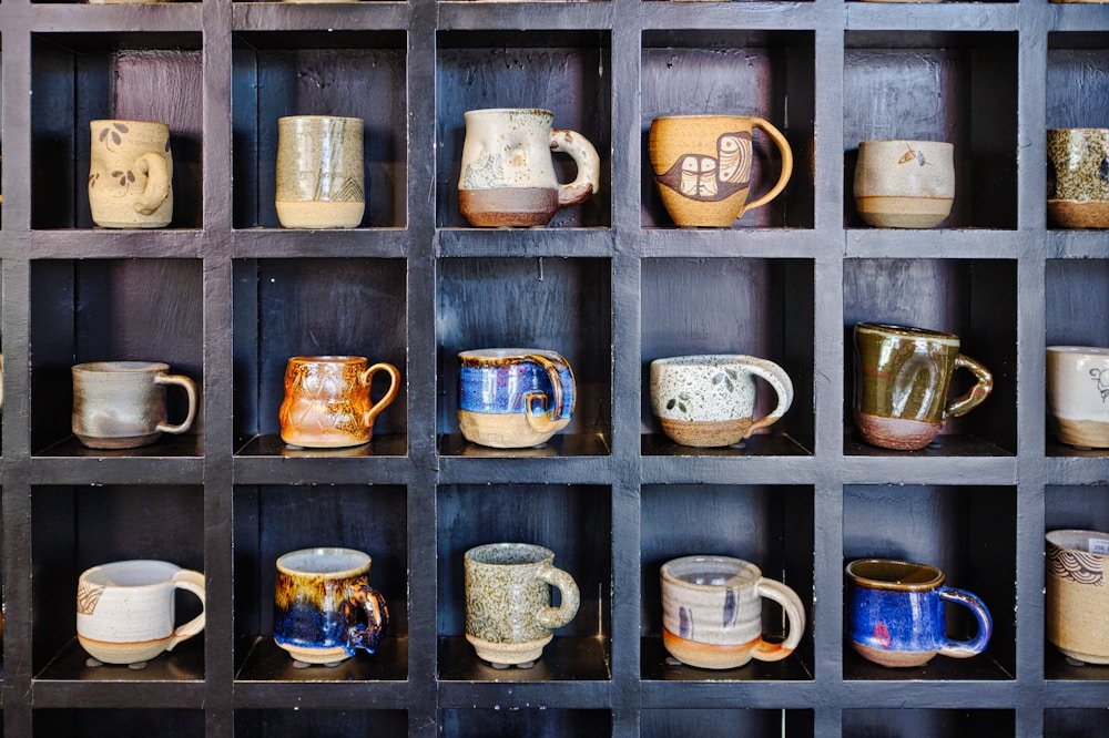 Shelf of hand-painted ceramic mugs from Mug & Muse pottery sessions